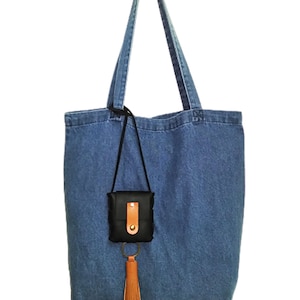 May include: A blue denim tote bag with a black leather pouch and a brown tassel attached to a gold key ring.