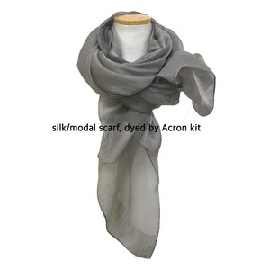 May include: A gray silk and modal scarf, dyed with an Acron kit. The scarf is draped over a mannequin's neck and shoulders.