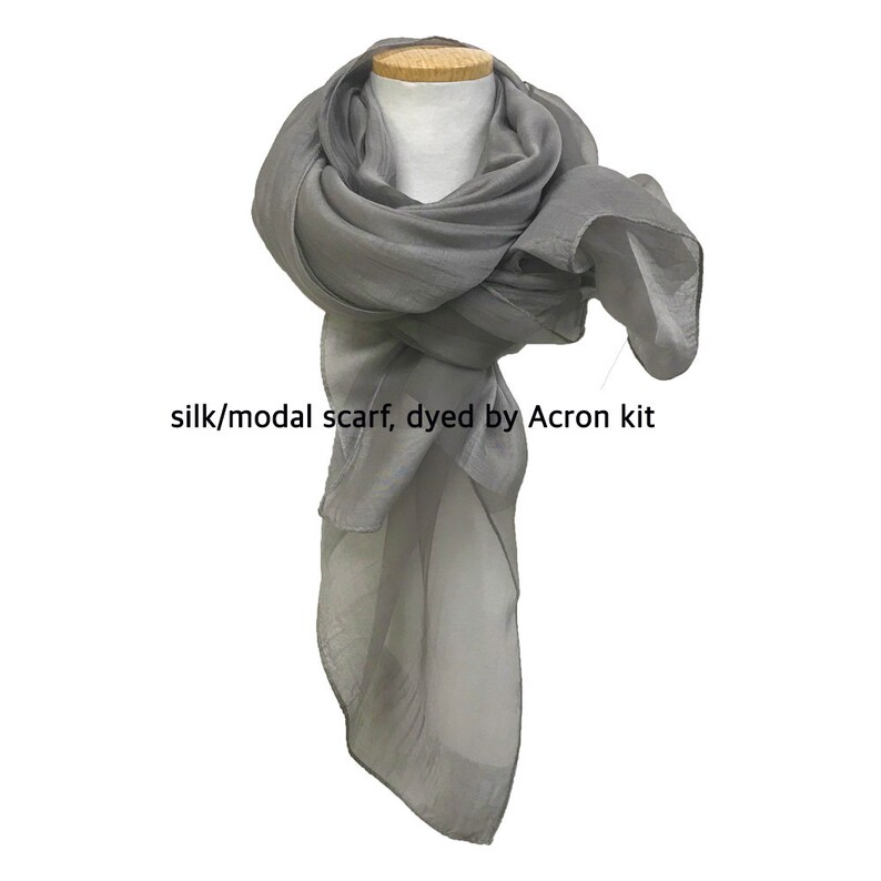 May include: A gray silk and modal scarf, dyed with an Acron kit. The scarf is draped over a mannequin's neck and shoulders.
