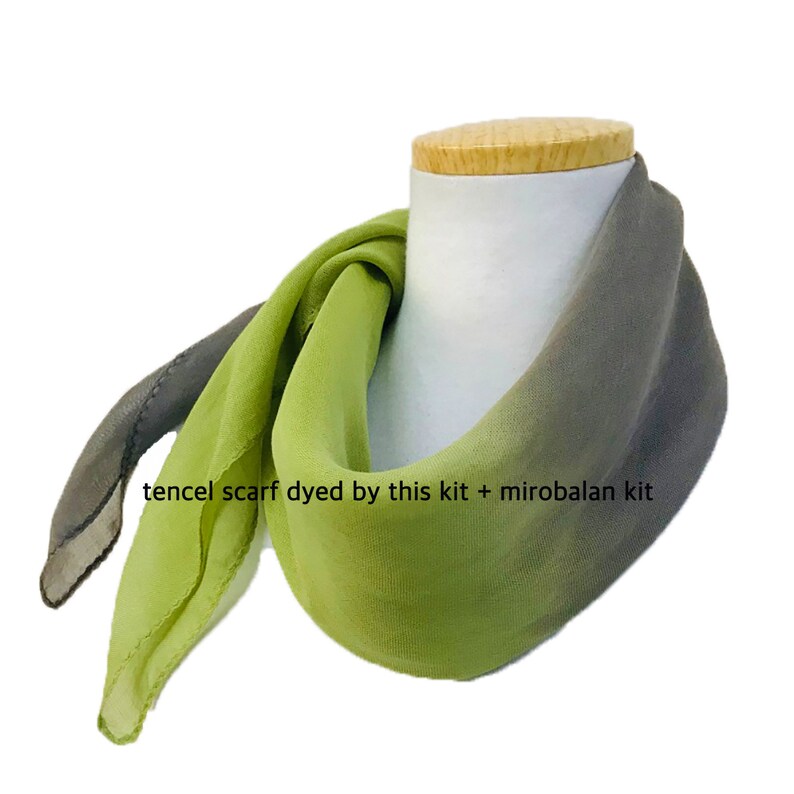 May include: A green and gray ombre tencel scarf dyed with a natural dye kit. The scarf is displayed on a white mannequin. "tencel scarf dyed by this kit + mirobalan kit" is written on the scarf.