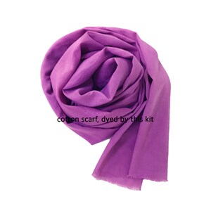 May include: A vibrant purple cotton scarf, dyed with a kit, is artfully draped. The scarf's fabric is soft and flowing, with a fringed edge. The text "cotton scarf, dyed by this kit" is visible.