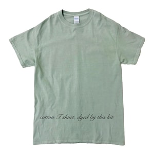 May include: A light green cotton T-shirt with short sleeves. The shirt has a crew neck and a relaxed fit. The text "cotton T shirt, dyed by this kit" is printed in black script at the bottom of the shirt.