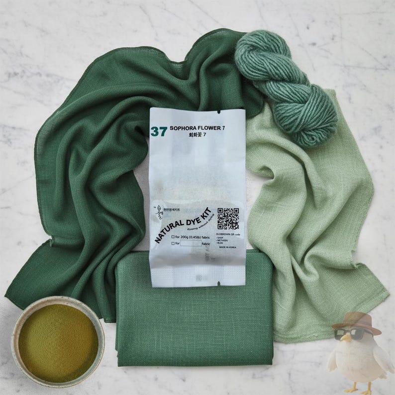 May include: An assortment of green fabric, yarn, and dye kit components. The kit includes a packet labeled "Sophora Flower 7" and a small container of green powder. Various shades of green textiles are arranged around the kit.
