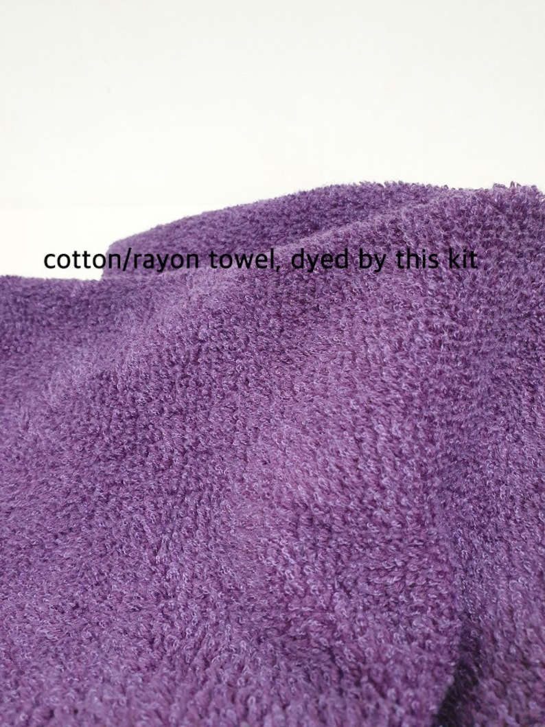 May include: Close-up of a textured, purple cotton/rayon towel. The towel has a soft, plush appearance. Text on the image reads: "cotton/rayon towel, dyed by this kit."