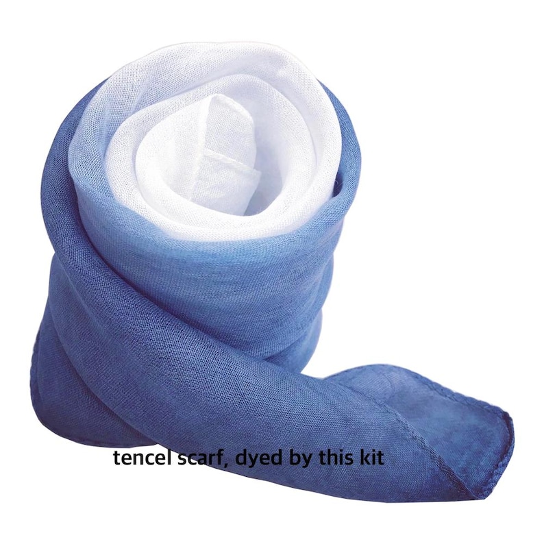 May include: Rolled tencel scarf with a gradient of colors from white to shades of blue. The scarf is tightly rolled, displaying the different color sections. The text "tencel scarf, dyed by this kit" is visible at the bottom.