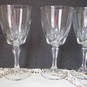 May include: Set of four clear glass wine glasses with a cut crystal design. The glasses have a tall, slender stem and a round base.