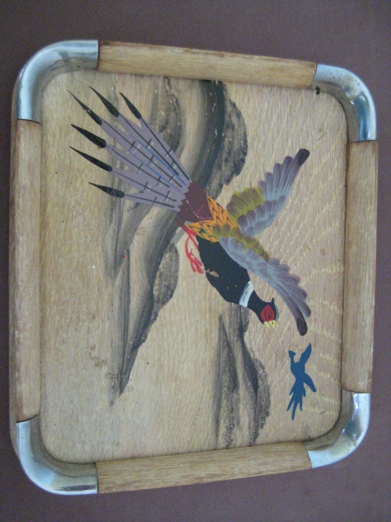May include: A rectangular wooden tray featuring a painted pheasant design. The bird is shown in flight with a black head, red details, and colourful wings. The tray has a light wood frame with metal corner accents.