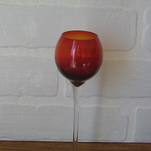Puede incluir: Un tallo de vidrio transparente alto con un cuenco redondo rojo. El vaso es perfecto para exhibir una sola flor o un pequeño ramo.