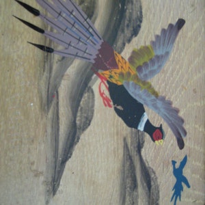 May include: Hand-painted artwork of a pheasant in flight, featuring a black body, red accents, and a detailed tail with purple and black feathers. The bird is set against a light brown wooden background with abstract grey and blue painted elements.