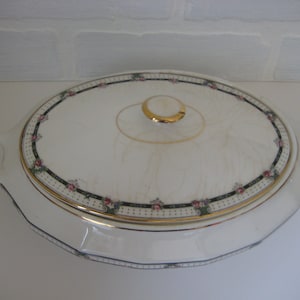 May include: White oval serving dish with a lid. The dish has a gold rim and a black and green floral design. The lid has a gold knob.
