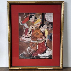 May include: Framed vintage Japanese artwork featuring figures in traditional attire. The artwork is set against a red mat and framed in a gold bamboo-style frame. The artwork depicts a scene with multiple figures in colorful robes.