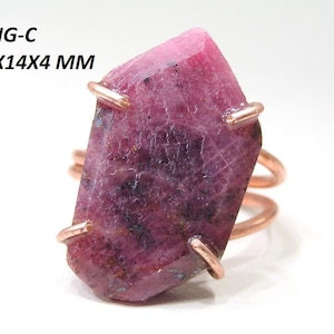 May include: A raw ruby ring with a copper band. The ruby is a deep pink color with dark inclusions and measures approximately 0.94 x 0.55 x 0.16 inches. The ring is labeled "RING-C" with the dimensions "24x14x4 MM".