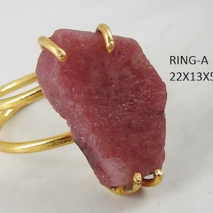 May include: Gold ring with a large, pink, rough-cut gemstone. The ring is double-banded and the stone is approximately 22x13x5 mm.