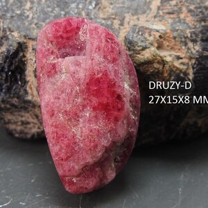 May include: A large, pink, semi-circular, rough-textured, druzy gemstone. The gemstone is approximately 27 x 15 x 8 mm.