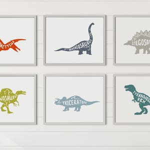 Puede incluir: Seis impresiones art&iacute;sticas enmarcadas de dinosaurios. Cada impresi&oacute;n presenta una silueta de dinosaurio diferente con su nombre en el interior. Los dinosaurios incluyen Pterodactylus, Brachiosaurus, Stegosaurus, Spinosaurus, Triceratops y Tyrannosaurus Rex. Los marcos son grises y el fondo es blanco.