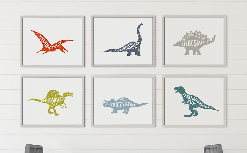 Puede incluir: Seis impresiones art&iacute;sticas enmarcadas de dinosaurios. Cada impresi&oacute;n presenta una silueta de dinosaurio diferente con su nombre en el interior. Los dinosaurios incluyen Pterodactylus, Brachiosaurus, Stegosaurus, Spinosaurus, Triceratops y Tyrannosaurus Rex. Los marcos son grises y el fondo es blanco.