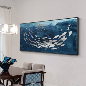 May include: A dining room with a modern design featuring a dark wood table with six chairs. The chairs have a blue and white patterned fabric. A large abstract painting of silver fish on a blue background hangs on the wall.