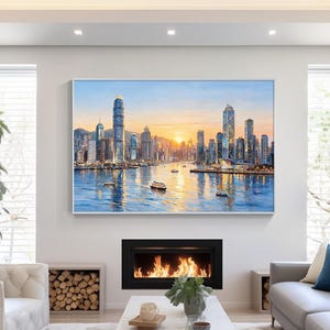 May include: A large rectangular wall art print depicting a Hong Kong city skyline at sunset with skyscrapers reflecting on the water, featuring boats in the harbor, painted in shades of blue, orange, yellow, and white, displayed above a fireplace.