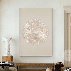 Könnte beinhalten: Ein großes, gerahmtes Kunstwerk mit einem kreisförmigen Design aus zahlreichen, sich überlappenden, irisierenden, muschelartigen Elementen. Das Kunstwerk befindet sich vor einem neutralen, beigefarbenen Hintergrund und wird in einem modernen Wohnraum mit neutralen Tönen und Akzenten aus Naturholz gezeigt.