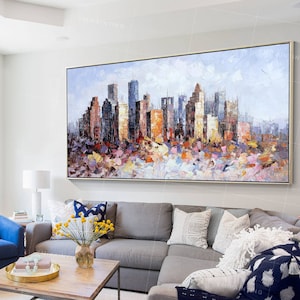 Puede incluir: Una pintura de un paisaje urbano con edificios coloridos y un cielo azul claro. La pintura est&aacute; realizada en un estilo texturizado con pinceladas visibles. La pintura est&aacute; enmarcada en un marco dorado.