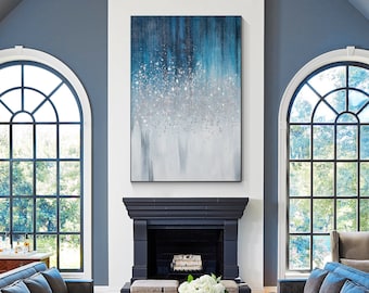 May include: A living room with two large windows, a fireplace, and two blue velvet sofas. The fireplace has a black mantel and a black hearth. The sofas are facing each other and there is a coffee table between them. There is a painting above the fireplace.