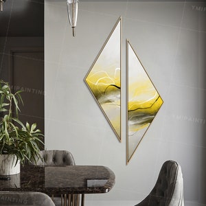Pode incluir: Duas pinturas abstratas em forma de diamante com moldura dourada. As pinturas estão sobre um fundo branco com linhas e formas abstratas amarelas, verdes e pretas.