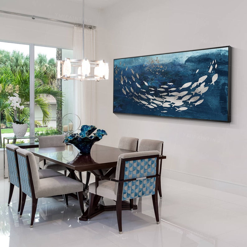 May include: A dining room with a modern design featuring a dark wood table with six chairs. The chairs have a blue and white patterned fabric. A large abstract painting of silver fish on a blue background hangs on the wall.