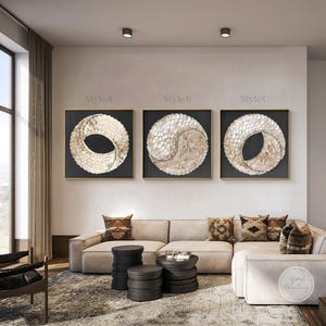Può includere: Tre pezzi di arte da parete astratta con un design circolare realizzato con pezzi di conchiglie bianche e dorate. I pezzi sono incorniciati in oro e hanno uno sfondo nero. Il testo "Style A", "Style B" e "Style C" è sopra ogni pezzo.