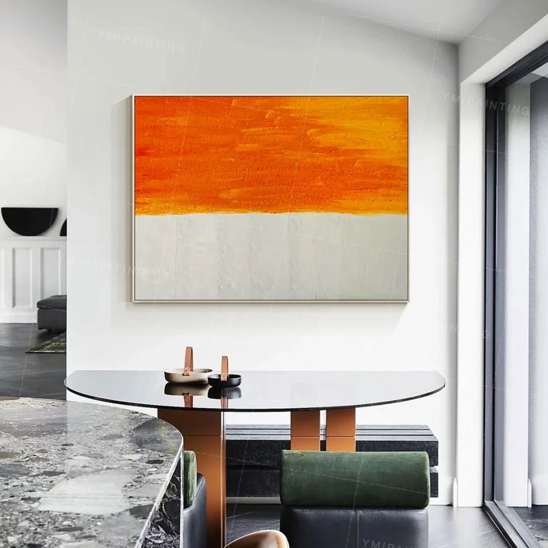Puede incluir: Pintura abstracta con un dise&ntilde;o de rayas horizontales naranja y blancas. La pintura est&aacute; enmarcada y colgada en una pared blanca en un interior moderno.