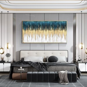 Op de afbeelding: Abstract schilderij met blauwe, gouden en witte kleuren in een moderne slaapkamer. Het schilderij hangt boven een bed met een zwarte deken en een zwart voeteneind.