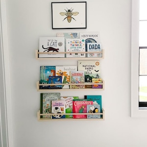 Stylish gender-neutral nursery bookshelf for decor and organization. Montessori-inspired design complements nursery art and wallpaper