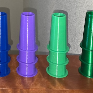 May include: A set of eight colorful plastic cones stacked in a row. The cones are yellow, pink, orange, blue, purple, green, and dark green.