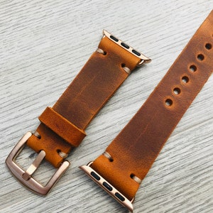 May include: Two brown leather watch bands with gold hardware. The bands are distressed and have a vintage look.