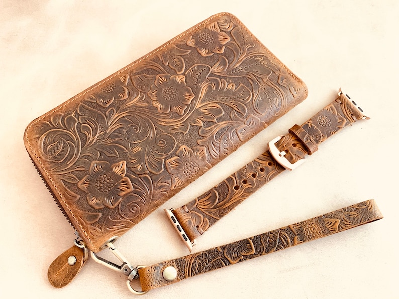May include: A brown leather wallet with a floral embossed design, a matching brown leather watch band, and a brown leather strap.