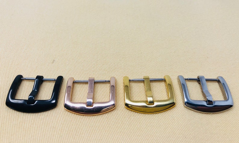 May include: Four watch band buckles in different finishes: black, rose gold, gold, and silver.