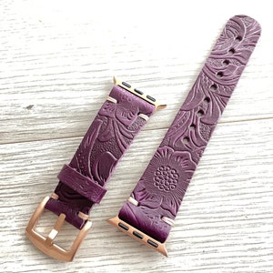 May include: A purple leather Apple Watch band with a floral embossed pattern and rose gold hardware.
