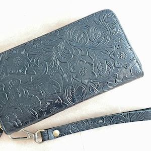 May include: A black leather wallet with a floral embossed design and a detachable wrist strap.