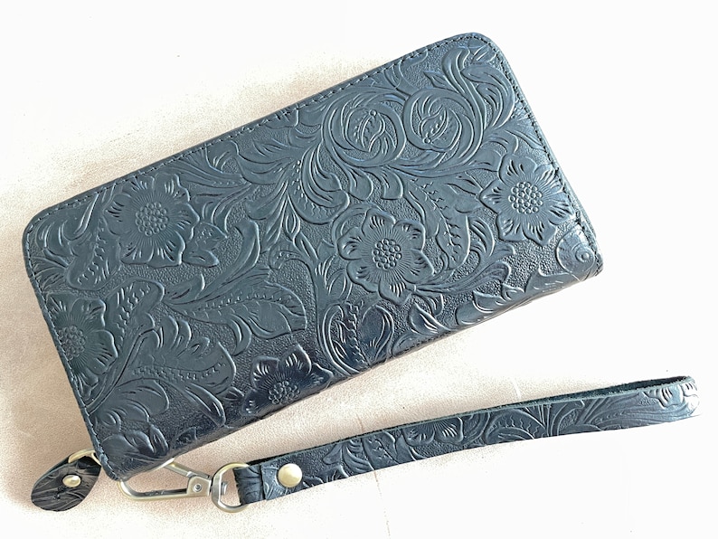 May include: A black leather wallet with a floral embossed design and a detachable wrist strap.