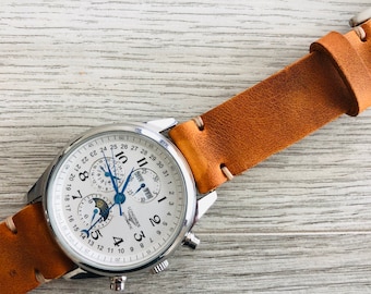 May include: A silver Longines Automatic watch with a white face and brown leather band. The watch has a date window, a moon phase indicator, and a chronograph.