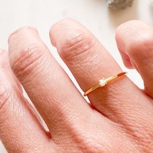 Peut inclure: Une délicate bague en or avec une petite pierre blanche au centre.