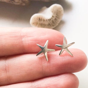 May include: A pair of silver starfish stud earrings. The earrings are small and delicate, and they are perfect for adding a touch of whimsy to any outfit.