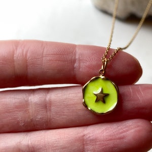 Puede incluir: Un collar de cadena dorada con un colgante verde lima que presenta una estrella dorada en el centro.