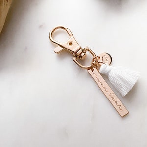 May include: Gold keychain with a white tassel and a charm that says "mama bear".
