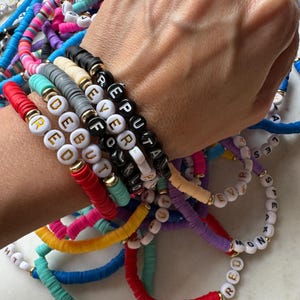May include: A stack of colorful beaded bracelets with letter beads spelling out words like "REPUTA", "EVER", "FOKLO", "DEBUT", "RED", "HT", "LES", "EVIE", "S", "M", "T", "D", "K", "MOND", and "MRED".