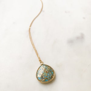May include: A gold chain necklace with a turquoise and gold teardrop pendant.