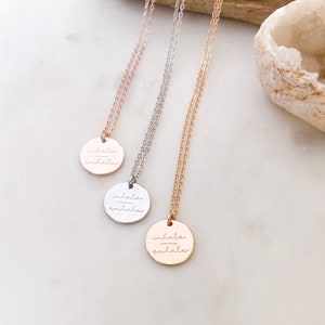 Könnte beinhalten: Drei zarte Halsketten mit runden Anhängern, auf denen "inhale exhale" in einer kursivschriftlichen Schriftart steht. Die Halsketten sind in Roségold, Silber und Gold.