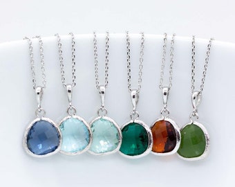 May include: Seven gemstone pendant necklaces in shades of blue, green, and orange. Each necklace features a coloured, faceted gemstone pendant set in a silver-coloured bezel, suspended from a fine silver chain. The necklaces are displayed against a white backdrop.
