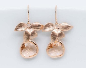 Può includere: Orecchini in oro rosa con un delicato design floreale e pietre di cristallo trasparenti.