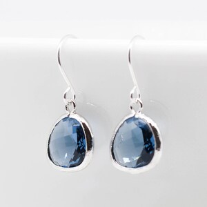 May include: A pair of silver dangle earrings with a light blue gemstone. The earrings have a simple design and are perfect for everyday wear.