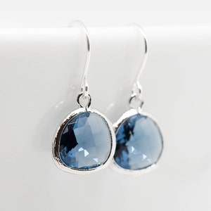 May include: A pair of silver dangle earrings with a round, faceted, light blue gemstone.